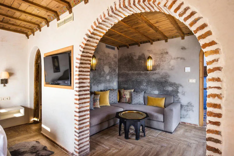 A brick arch opening from a bedroom into a sitting area with a low Moroccan table