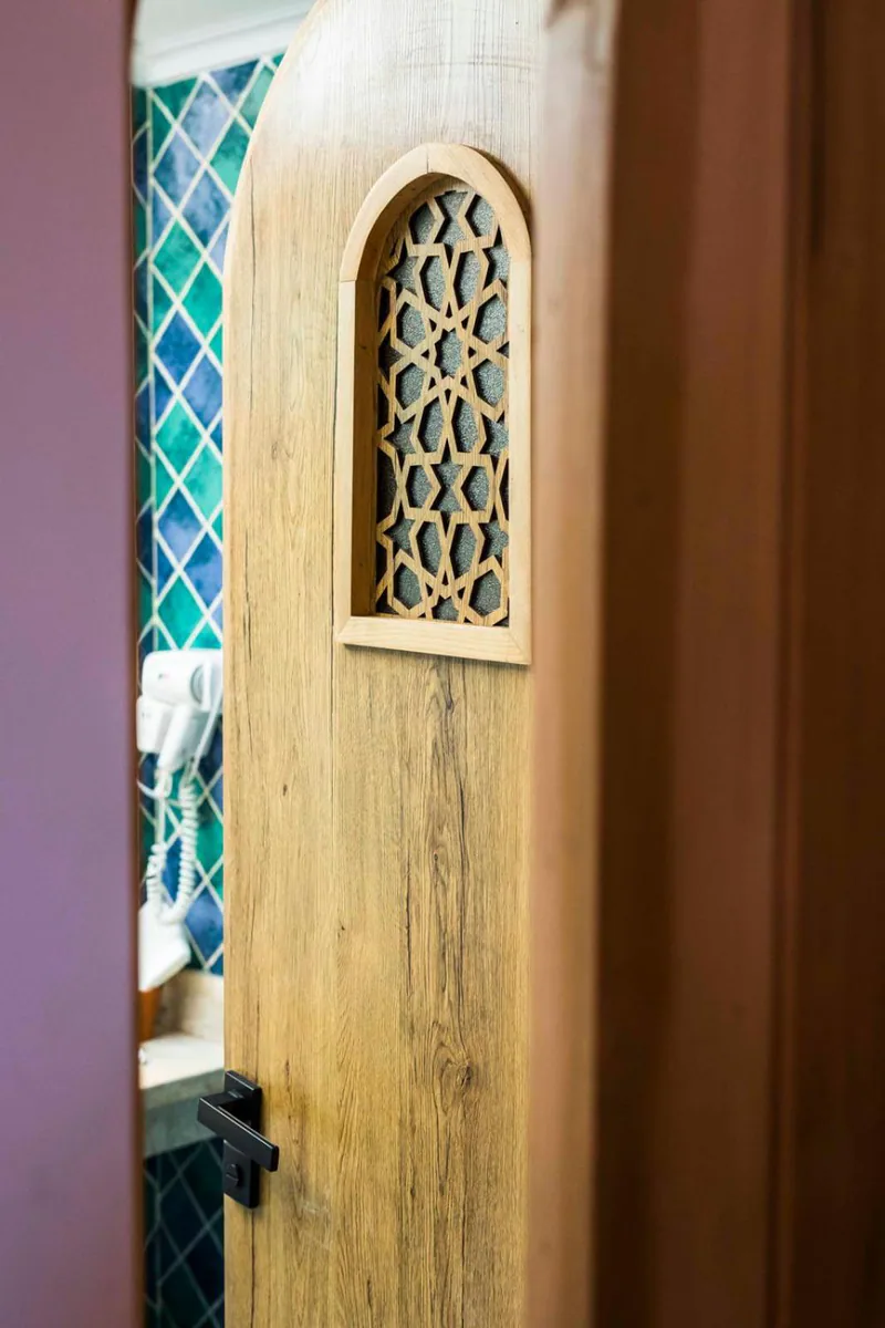 A carved plaster window with coloured glass set into a white wall
