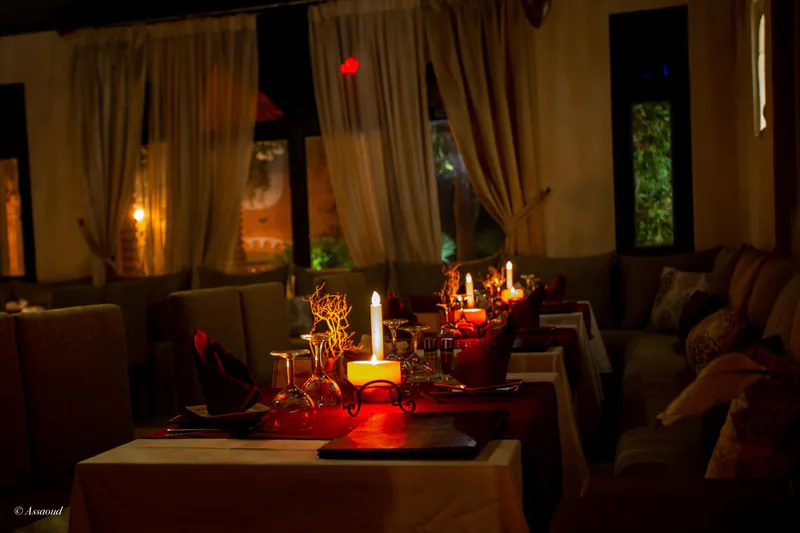 A candlelit dinner table set in the restaurant, with curtains drawn back from the windows