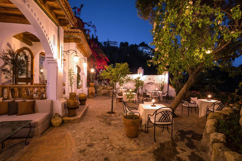 The garden courtyard at blue hour, its arcades and orange trees lit from below