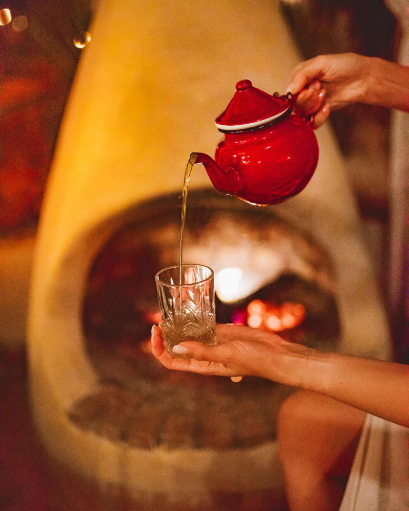 Mint tea poured from a red teapot into a glass
