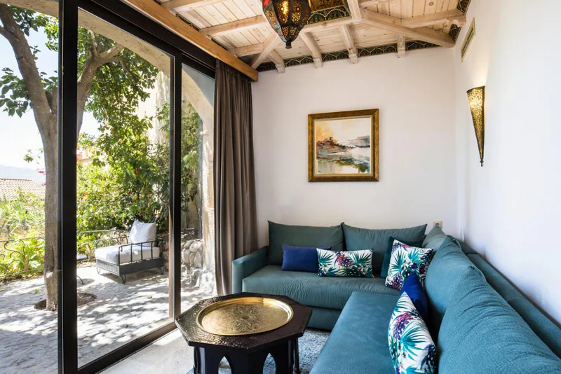 A teal sofa with embroidered cushions beside a glass door onto a private terrace