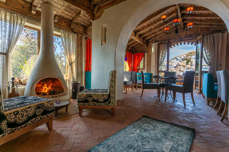 A lit fireplace in a vaulted salon that opens to a terrace above the town