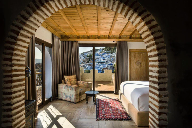 A brick arch inside a suite, framing the bed, the sitting area and the terrace above the medina